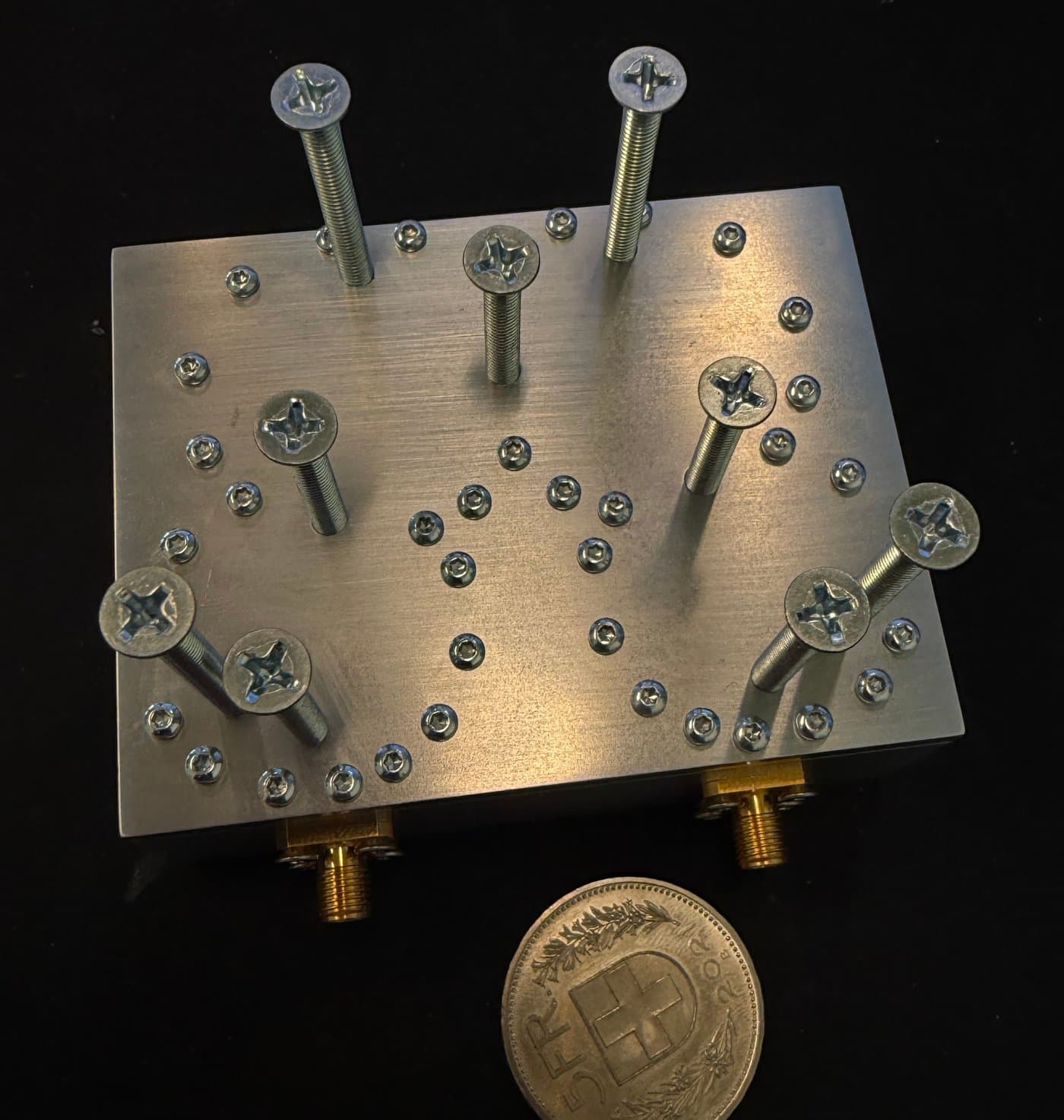 Mechanically tunable L-band coaxial Stepped-Impedance Resonator filter with adjustment screws, next to a Swiss franc coin